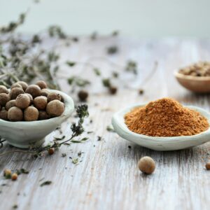 An artistic display of whole and ground spices in ceramic bowls on a rustic wooden surface, emphasizing culinary tradition.
